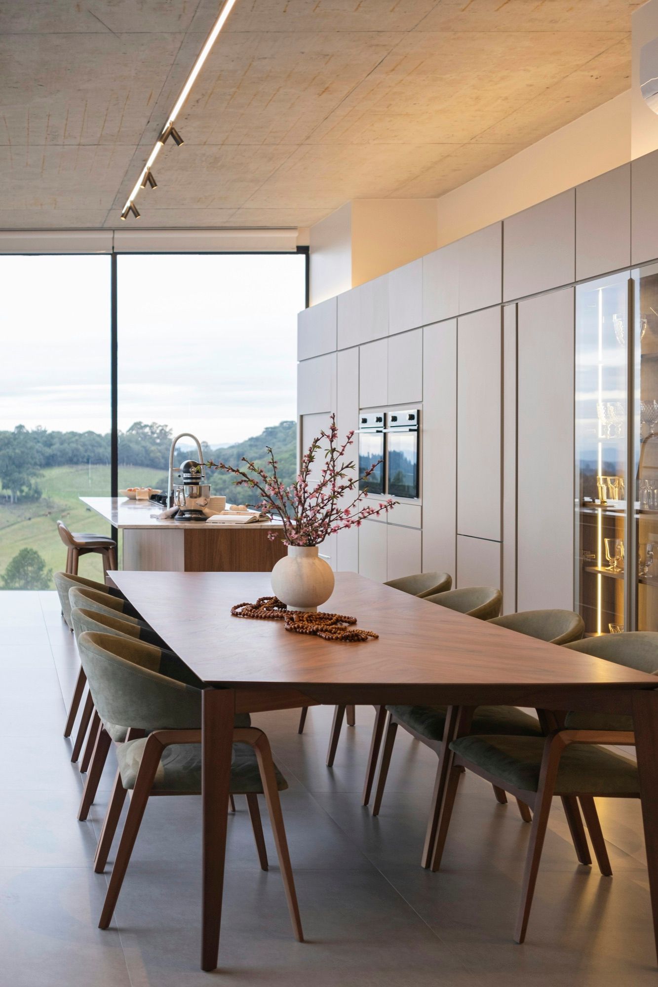 A dining room with a long wooden table before a wide window