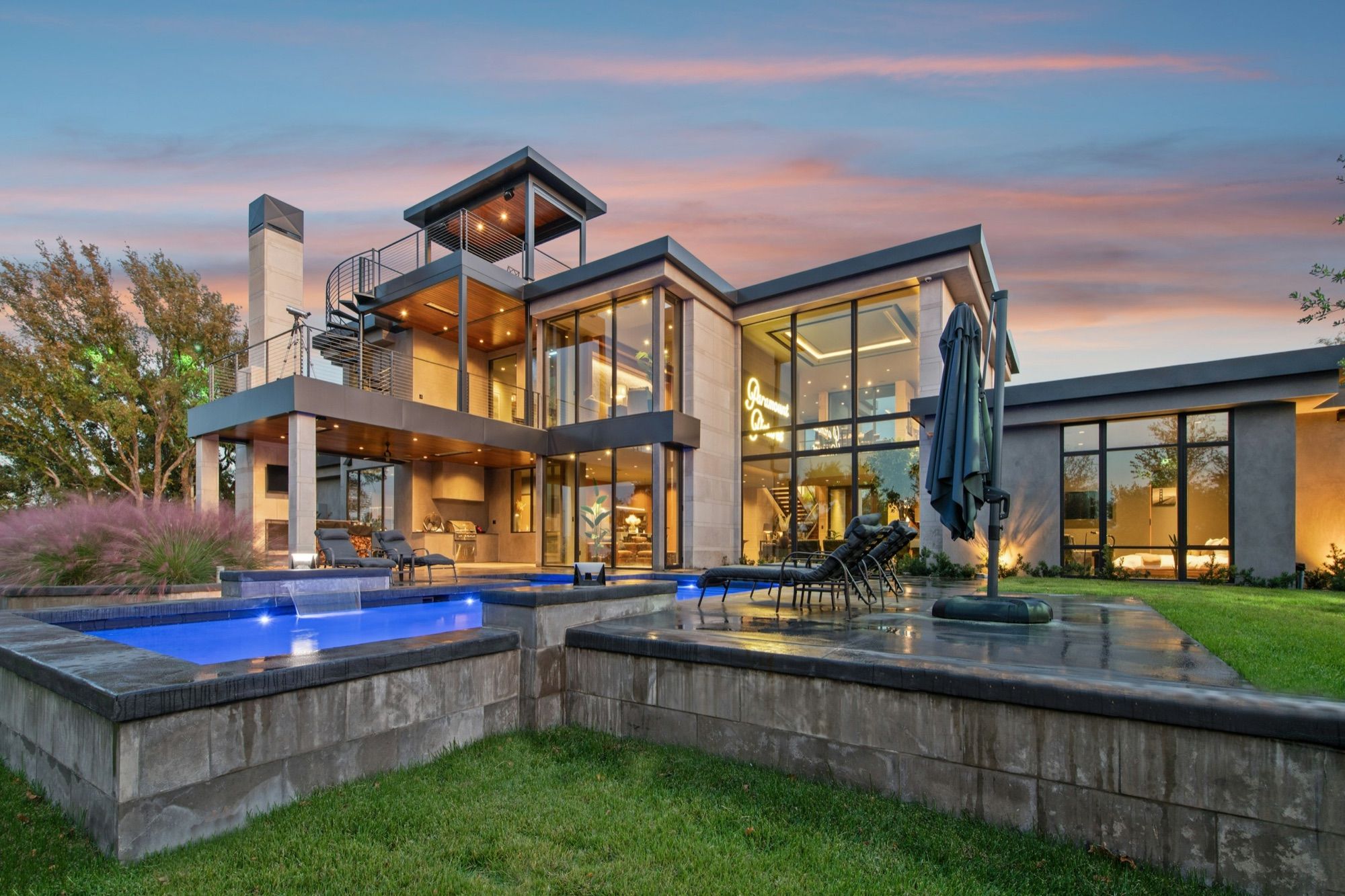 A new modern house with its pools lit at dusk