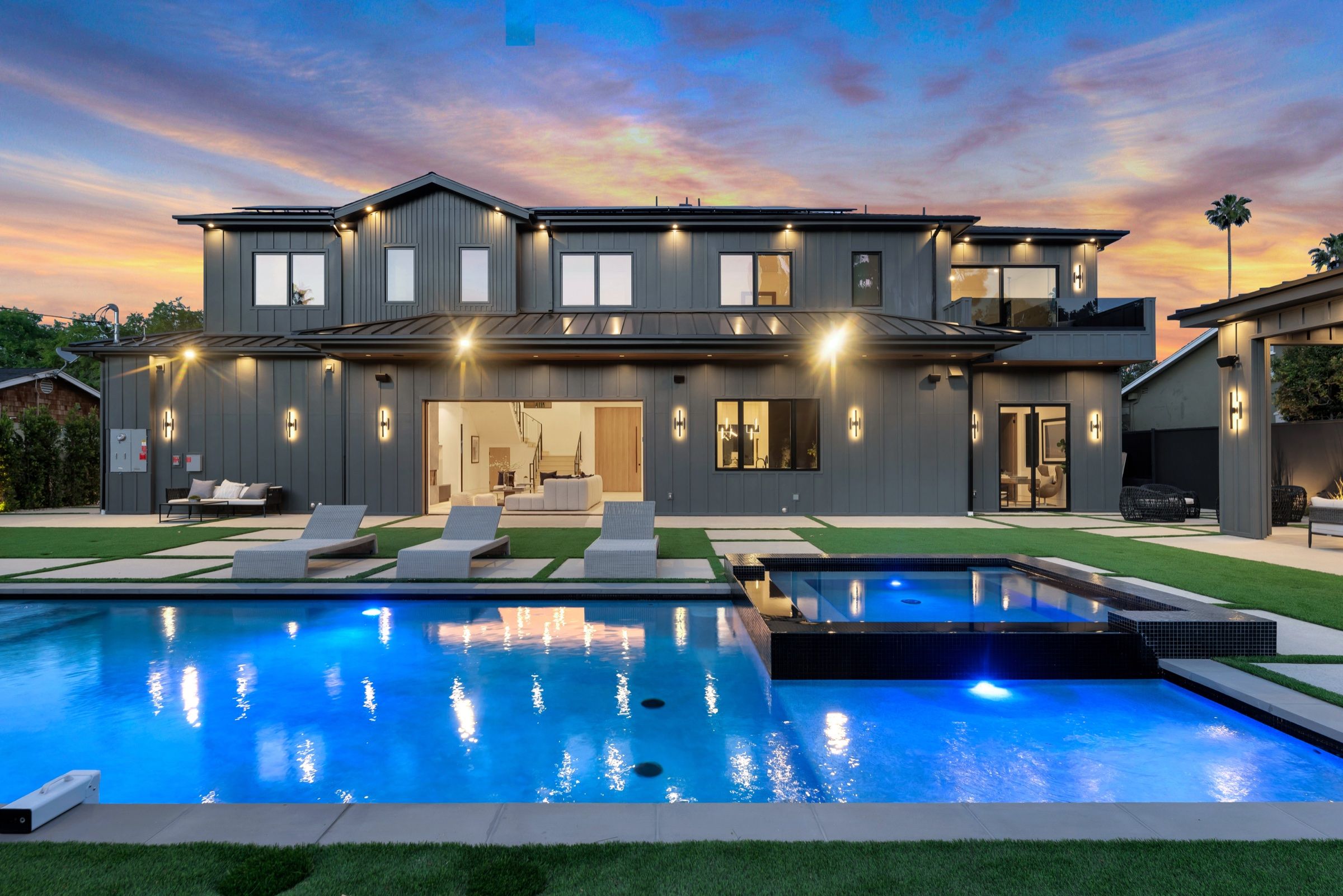 The pool and spa lit blue at dusk, the house beyond
