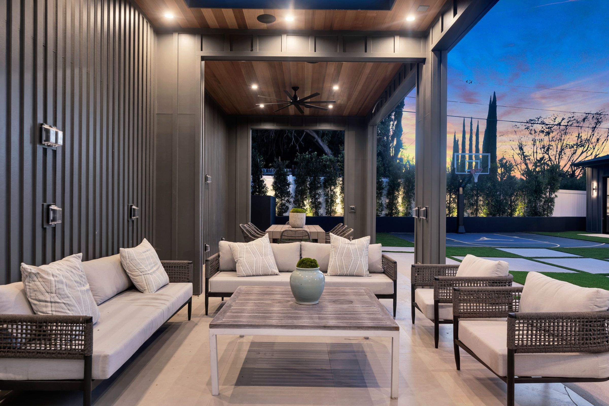 An outdoor lounge under a timber ceiling, the pool beyond